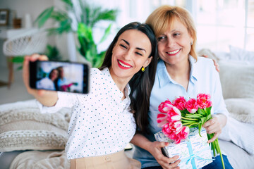 Memory photo. Happy mother and daughter making selfie on smart phone at home on the couch. Birthday, Mothers day, women's day, retired, family, relation, motherhood. - 773486119