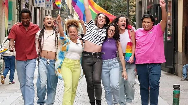 Diverse group of young people celebrating gay pride festival day - Lgbt community concept with guys and girls hugging together outdoors - Multiracial trendy friends standing on streets
