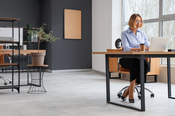Mature businesswoman working with laptop in modern office