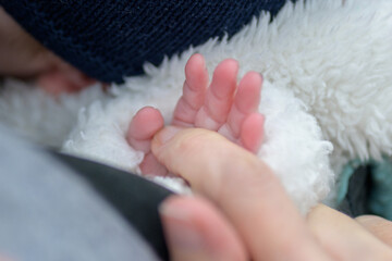 Extreme close up of the hand of little baby holding mothers hand with his little fingers outdoor