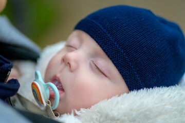 Extreme close up of little baby sleeping with a pacifier and a blue hat