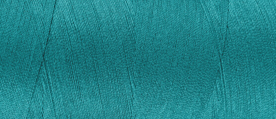 Texture of turquoise color threads in spool close up, macro. Wide banner, header of sewing threads...