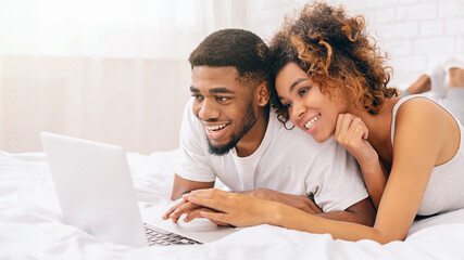 Couple enjoying content on a laptop in bed