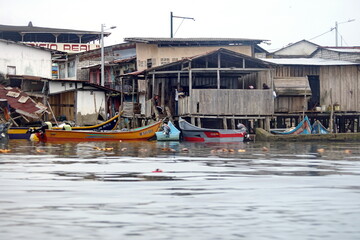 Fototapeta na wymiar Boats moored in front of wooden shacks in Limones, Esmereldas, Ecuador