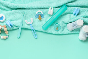 Towel with children's toothbrushes, socks and pacifiers on turquoise background