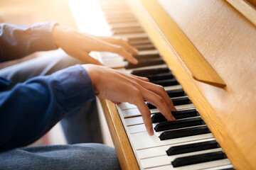 Male hands playing melody on the piano keys, closeup