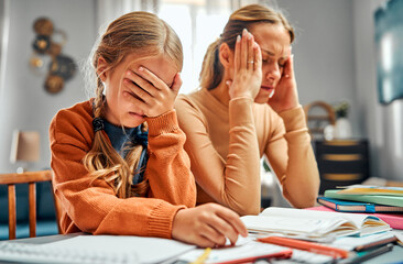Learning disability. Depressed child covering eyes with hand while sitting by loaded table with stressed mom