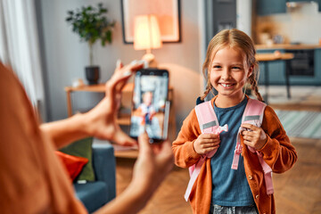 Picture for relatives. Charming kid posing in front of cellular phone for distant family members