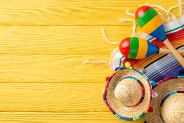 Fotobehang Cinco de Mayo top view scene: sombreros and maracas on display. Colorful serape adorn the yellow wooden desk. Space for text © ActionGP
