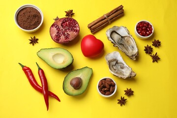Natural aphrodisiac. Different food products and red decorative heart on yellow background, flat lay