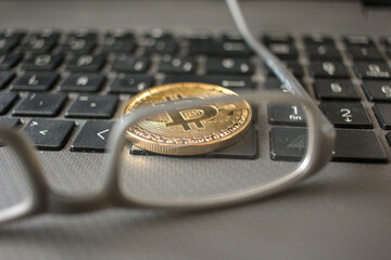 a pair of glasses, a laptop keyboard and a Bitcoin