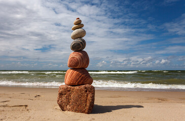 Stone zen pyramid made of colorful pebbles on the beach against a stormy sea.