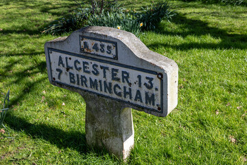 Milestone marker A435 Birmingham, Alcester old stone or concrete vintage sign on grass background