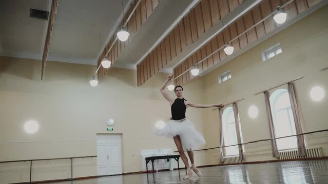 Professional ballerina in pointe shoes and white ballet tutu makes pirouette