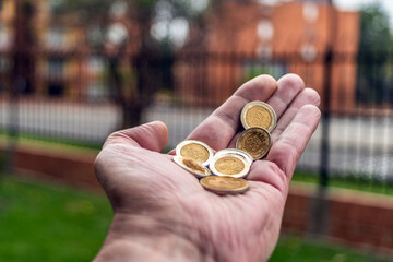 Man holding coins in the palm of his hand: personal finance and home economics concept."