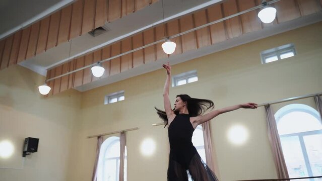 A prima ballerina spins on one leg in the hall 