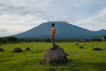 A bare-chested man with an athletic build, after morning exercises, admires a gorgeous view of the...