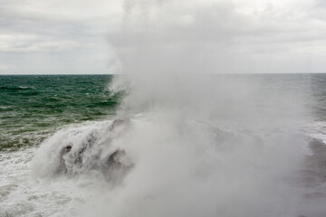 Waves hitting a sea rock with great force.