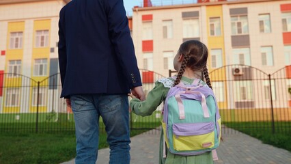 small child hand father hand. father leads child daughter hand school. large children school building. teaching children education. child parent school lesson. children time study. kid backpack. kid