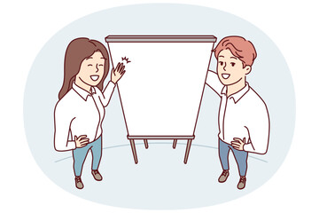 Man and woman office employees stand near empty flipchart carry out business presentation. Top view of guy and girl pointing with hands at sheet of paper for advertising services