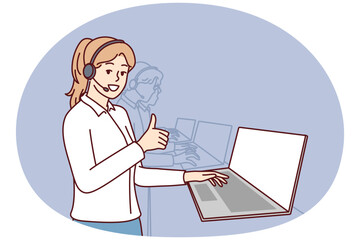 Woman in headphones for call center stands near laptop and looks at camera showing thumbs up. Girl employee of psychological support service or software user consultation smiling