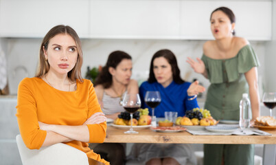 Obraz na płótnie Canvas Quarrel during friendly gatherings, three women friends yell at their young sister, offend, say offensive words, accuse them of lying, accuse of inappropriate behavior, gossip