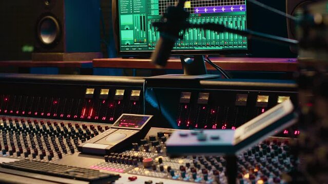 Empty control room running daw software interface on monitor to use in recording and editing audio files, adjusting volume levels. Professional studio having sliders and equalizer.