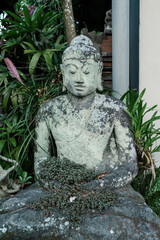 Weathered stone stature of a sitting buddha. Ubud, Bali, Indonesia.