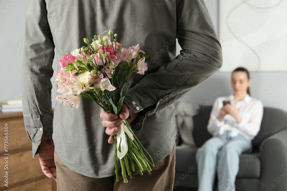 Poster Man hiding bouquet of flowers for his beloved woman indoors, closeup