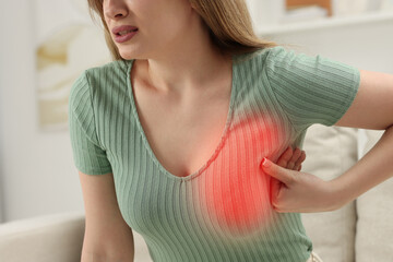 Young woman suffering from breast pain at home, closeup