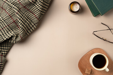 Book, glasses, candle, plaid, with cup coffee on beige background. Leisure concept, reading a book. Flat lay, top view