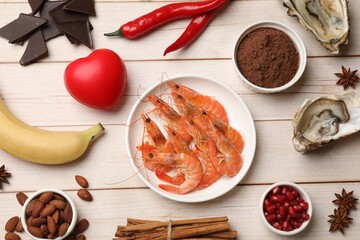 Natural aphrodisiac. Different food products and red decorative heart on light wooden table, flat...