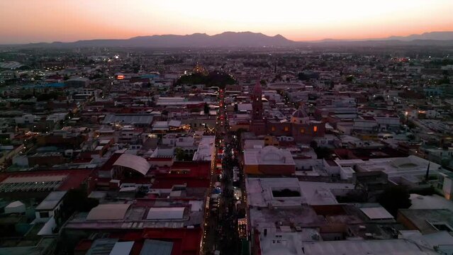 Dolly in en vista aerea de dron desde el centro hist&oacute;rico de Aguascalientes, M&eacute;xico con vista hacia el poniente de la ciudad y al cerro del muerto durante el atardecer.