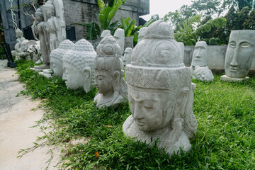 Heads of Buddha statues on the grass for sale. In the backround are easter island statues. Ubud,...