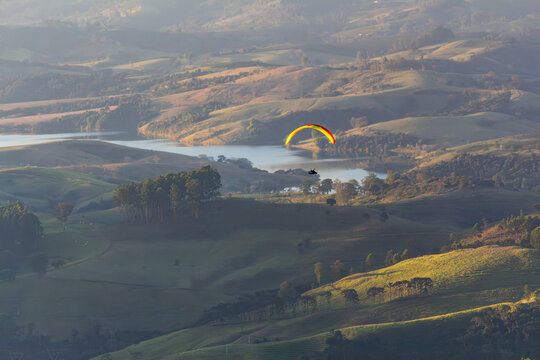 Paraglider se preparando para o pouso - PO&Ccedil;OS DE CALDAS, MG, BRAZIL - JULY 22, 2023: Paraglider at low altitude over the Lambari river region preparing for landing.