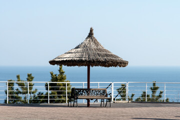 View of the straw parasol and table bench on the seaside cliff