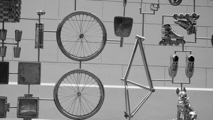 A wall of metal parts and objects, including a bicycle, a pair of skates