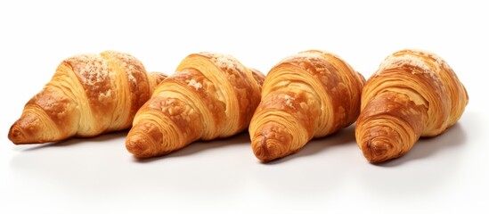 Four delicious croissants placed neatly in a row on a clean white surface, showcasing their golden flaky crust