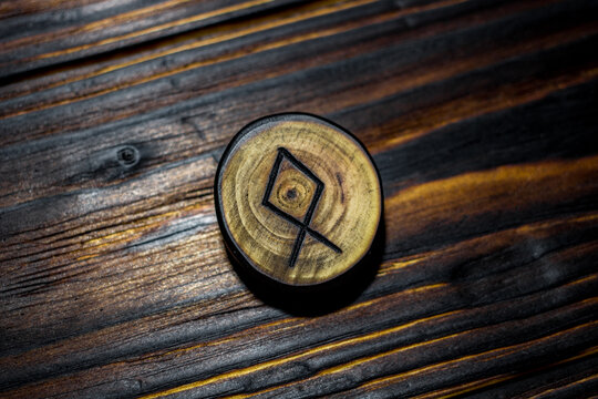 Rune Odal (Othala) carved from wood on a wooden background - Elder Futhark