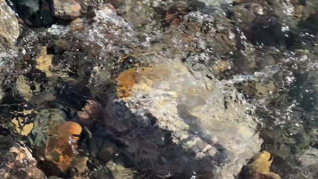Tight closeup of clear river water bubbling over rocks