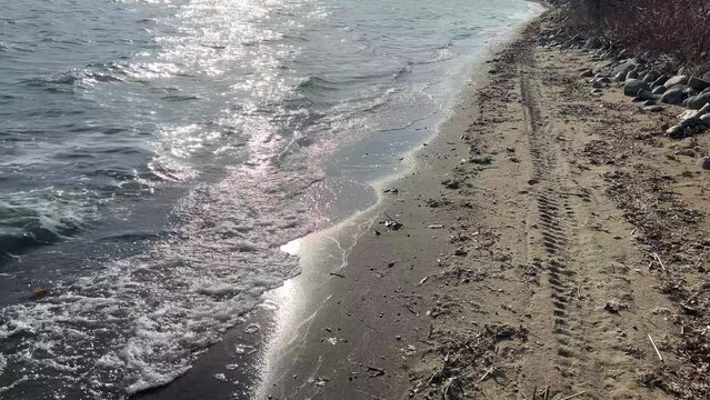 First-person-view walking along a sandy rocky lake beach