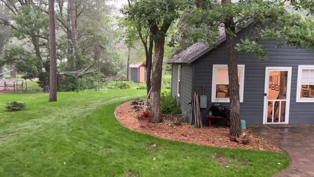 Pan right across cottage scene in a heavy downpour