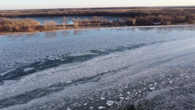 High aerial flyover of broken ice on a freezing lake near shore