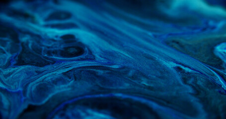 Glitter liquid spill. Acrylic paint mix. Defocused blue black color shimmering dust particles water...