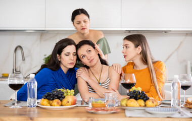 Frustrated and distressed Spanish woman sits in kitchen and complains to her female friends, talks about her difficulties at work, problems, vicissitudes. Women friends give advice, reassure, support
