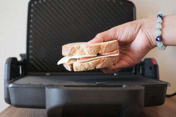 A person is retrieving a grilled sandwich from the grill - obrazy, fototapety, plakaty