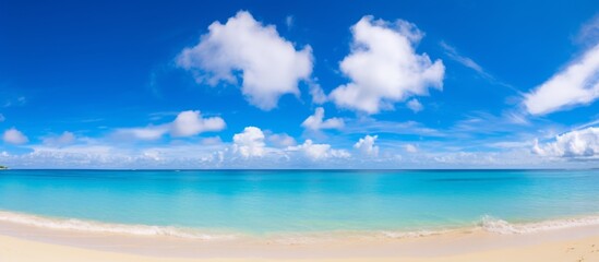 The serene beach offers a breathtaking view of the crystal clear blue ocean water and the white fluffy clouds in the sky
