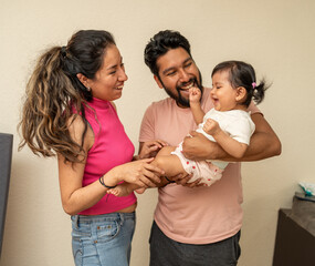 portrait of a happy young hispanic couple with a baby, latin family smiling cheerfuly