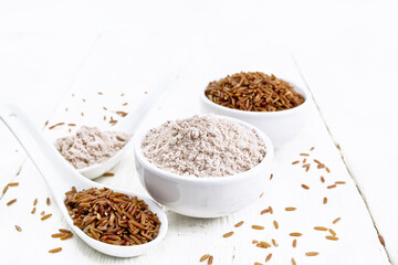 Flour red rice in bowl and spoon on white wooden board