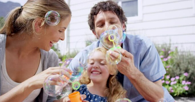 Family, relax in garden with bubbles and fun together outdoor, parents and young child with game and toys. Liquid soap, happiness and people in backyard at home, playful and laughter with bonding
